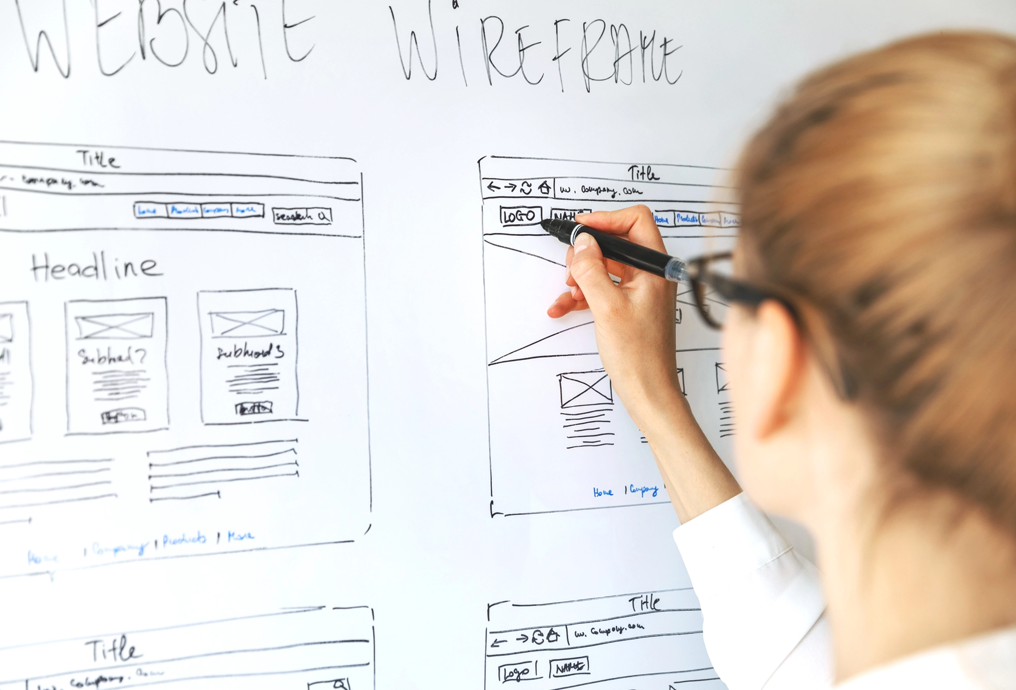 Person sketching a website wireframe on a whiteboard, symbolizing UnifyBoard's intuitive Software Solutions design and meticulous planning.